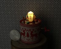 Miniature merry go round hand crank automaton with ligt up cream lidded mug and a parade of gingerbread people, ribbon candy, cupcake and French macarons