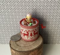 Miniature merry go round hand crank automaton with ligt up cream lidded mug and a parade of gingerbread people, ribbon candy, cupcake and French macarons