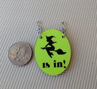 1:12 scale dollhouse Halloween oval sign featuring flying witch "is in" on bright yellow glow-in-the-dark background