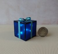 Miniature light up gift box in translucent blue with a light blue shimmery gift bow Battery lighted festisve gift box for mini holiday scene display REF Blue