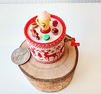 Miniature merry go round hand crank automaton with ligt up cream lidded mug and a parade of gingerbread people, ribbon candy, cupcake and French macarons