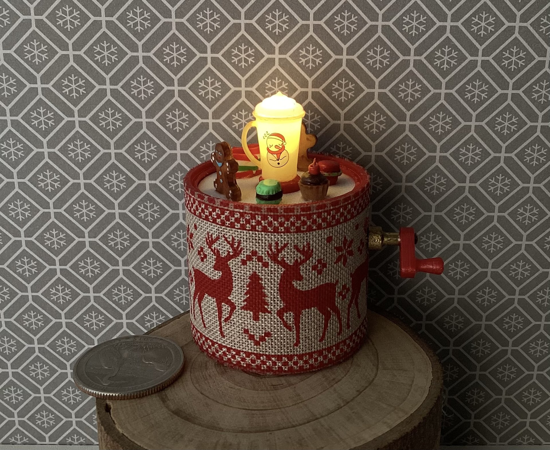Miniature merry go round hand crank automaton with ligt up cream lidded mug and a parade of gingerbread people, ribbon candy, cupcake and French macarons