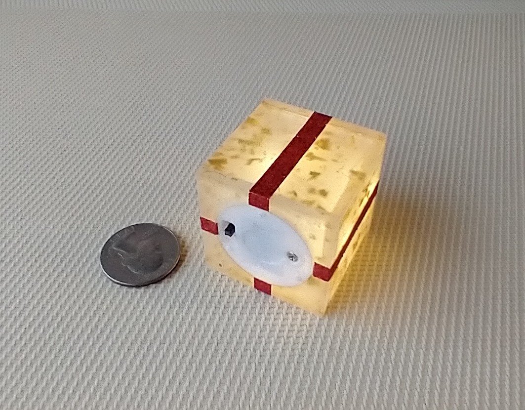 Miniature light up gift box in golden flakes with a  red gift bow Battery lighted festive gift box for mini holiday scene display REF Golden flakes red bow