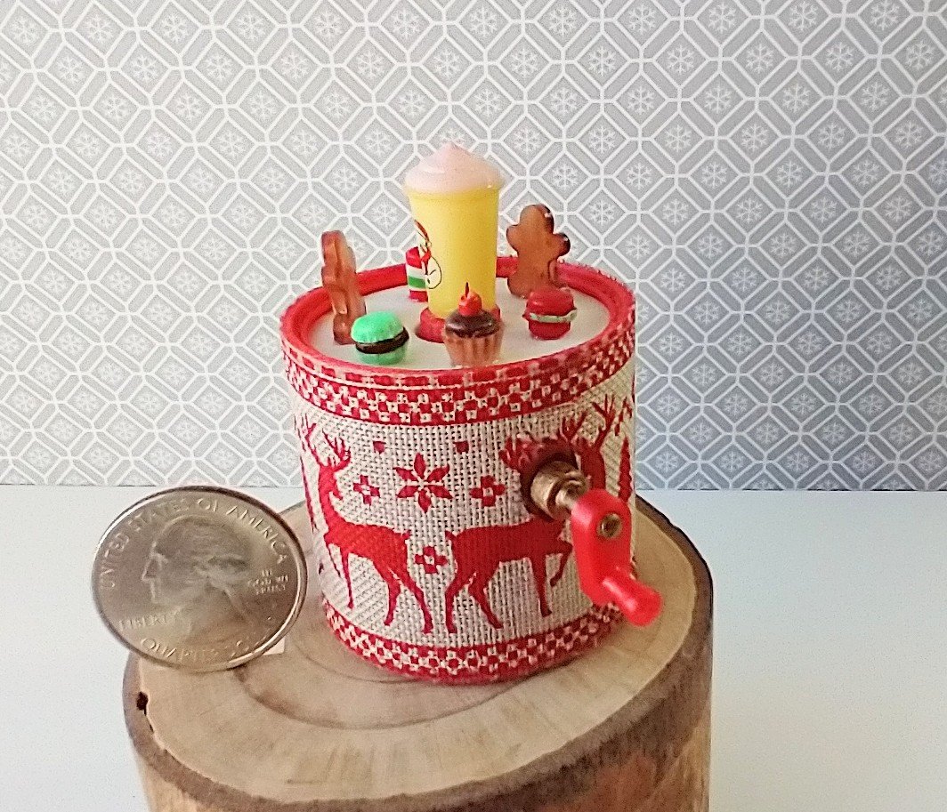 Miniature merry go round hand crank automaton with ligt up cream lidded mug and a parade of gingerbread people, ribbon candy, cupcake and French macarons