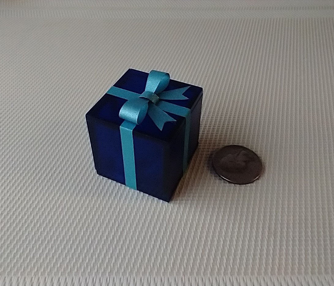 Miniature light up gift box in translucent blue with a light blue shimmery gift bow Battery lighted festisve gift box for mini holiday scene display REF Blue