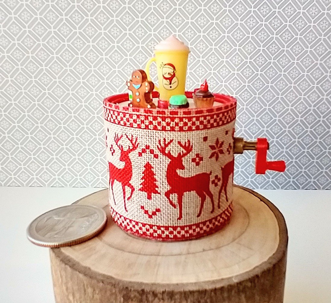 Miniature merry go round hand crank automaton with ligt up cream lidded mug and a parade of gingerbread people, ribbon candy, cupcake and French macarons