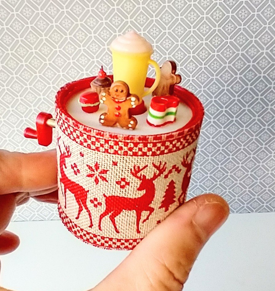 Miniature merry go round hand crank automaton with ligt up cream lidded mug and a parade of gingerbread people, ribbon candy, cupcake and French macarons
