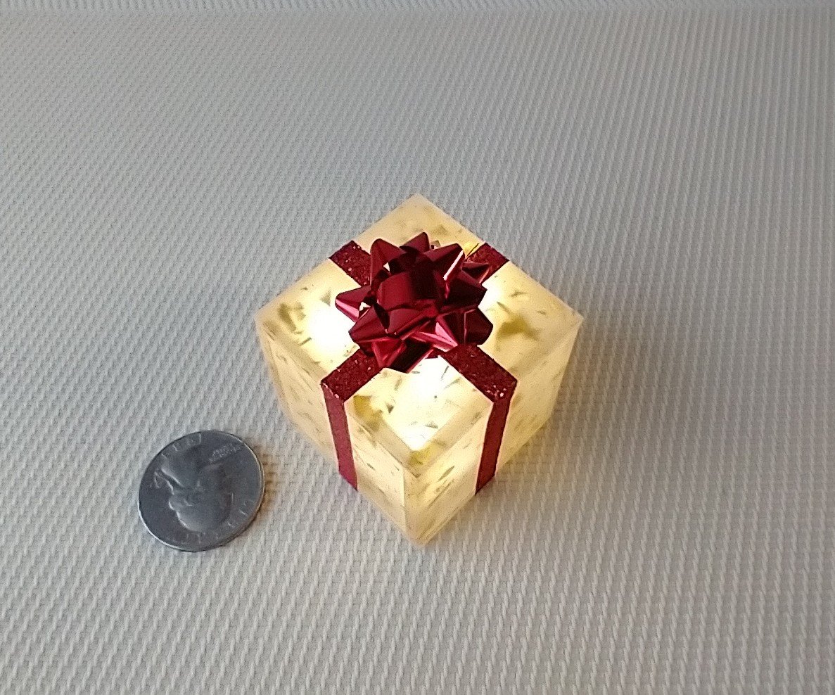 Miniature light up gift box in golden flakes with a  red gift bow Battery lighted festive gift box for mini holiday scene display REF Golden flakes red bow