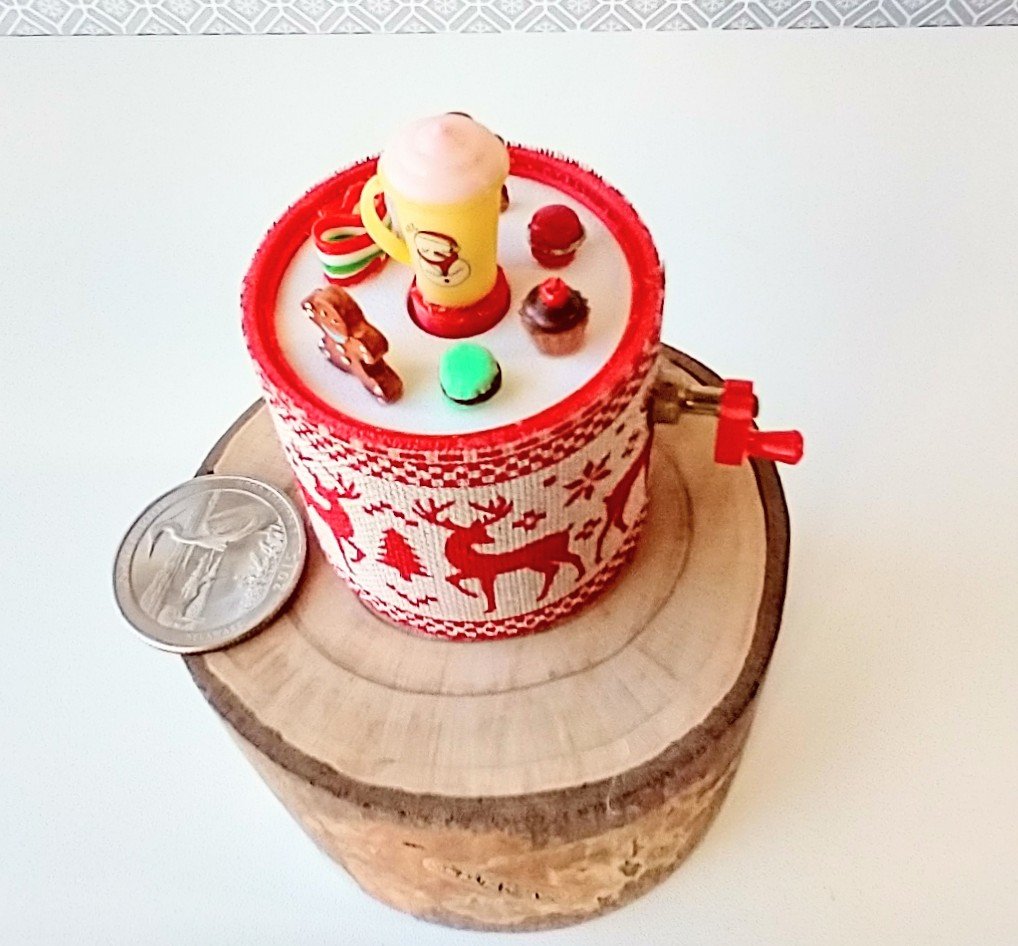 Miniature merry go round hand crank automaton with ligt up cream lidded mug and a parade of gingerbread people, ribbon candy, cupcake and French macarons