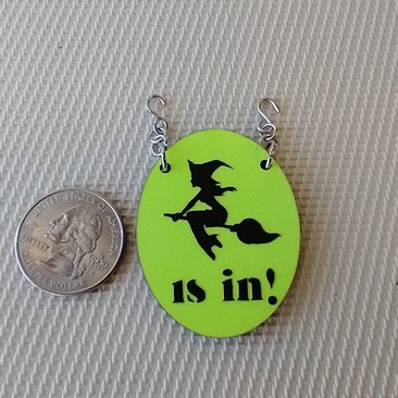 1:12 scale dollhouse Halloween oval sign featuring flying witch "is in" on bright yellow glow-in-the-dark background