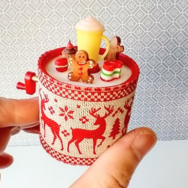 Miniature merry go round hand crank automaton with ligt up cream lidded mug and a parade of gingerbread people, ribbon candy, cupcake and French macarons